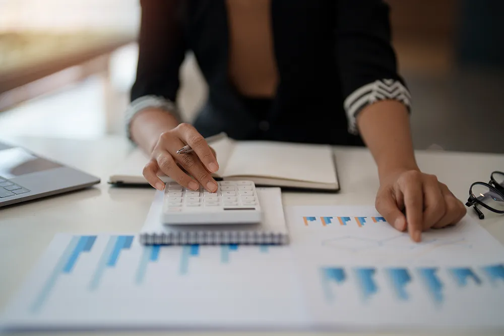 Both hands over printed blue bar charts and a calculator