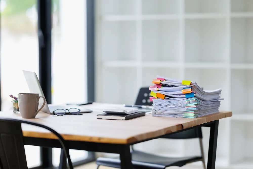 Stack of tabbed paperwork on a desk beside a calculator